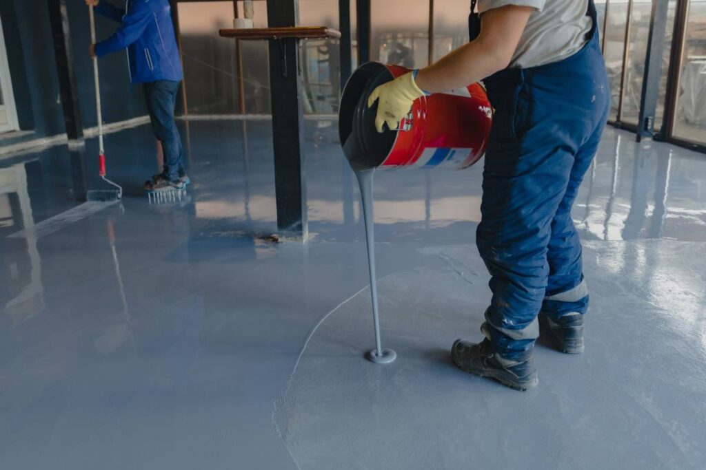 The worker applies gray epoxy resin to the new floor