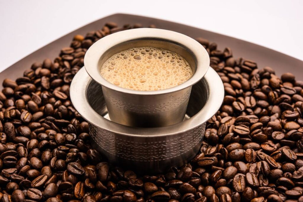 South Indian Filter coffee served in a traditional tumbler or cup over roasted raw beans