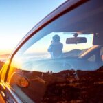 Woman photographing landscape standing near the car
