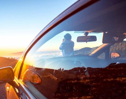 Woman photographing landscape standing near the car