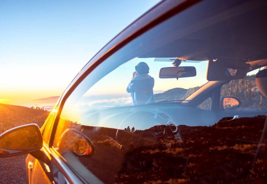 Woman photographing landscape standing near the car