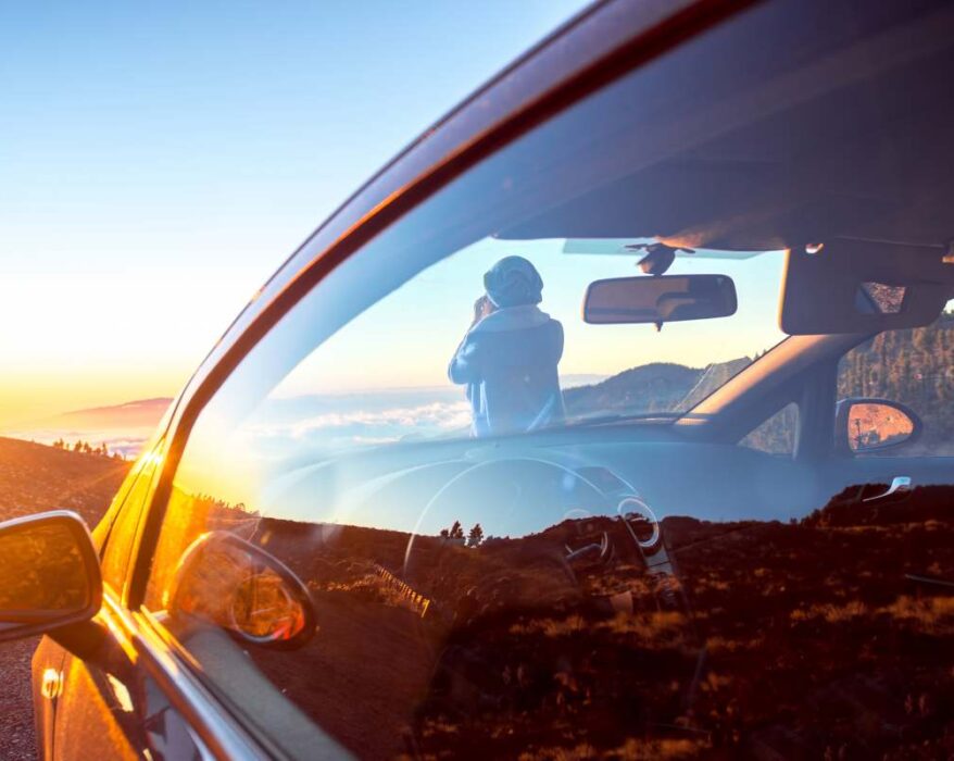 Woman photographing landscape standing near the car