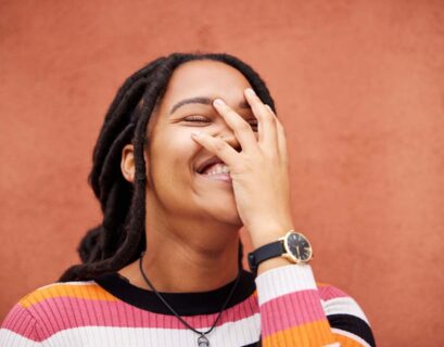 Happy, laughter and freedom with a black woman on an orange background outdoor for joy or humor. Fu
