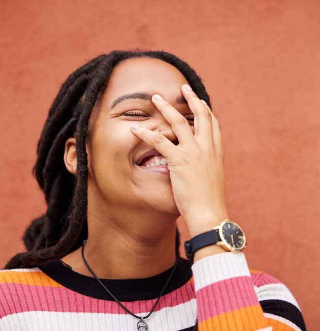 Happy, laughter and freedom with a black woman on an orange background outdoor for joy or humor. Fu