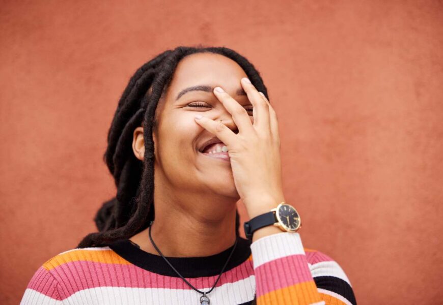 Happy, laughter and freedom with a black woman on an orange background outdoor for joy or humor. Fu