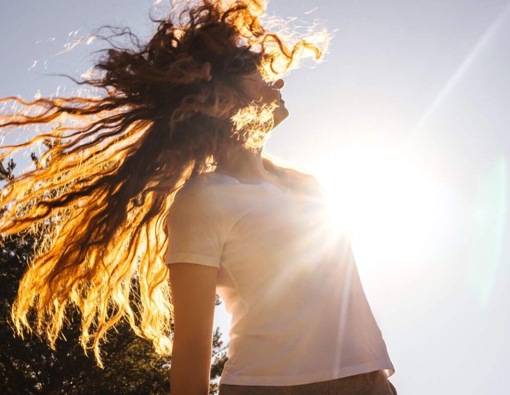 Happy girl with long hair in sunshine.